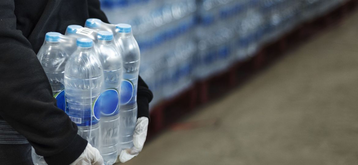 Woman carrying drinking waters with gloved hands during coronavirus pandemic